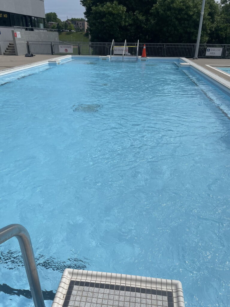 Outdoor commercial swimming pool with shallow area and safety signs